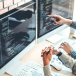 รับออกแบบเว็บไซต์ นักพัฒนาสองคนกำลังทำงานแก้ไขเว็บไซต์มืออาชีพบนคอมพิวเตอร์